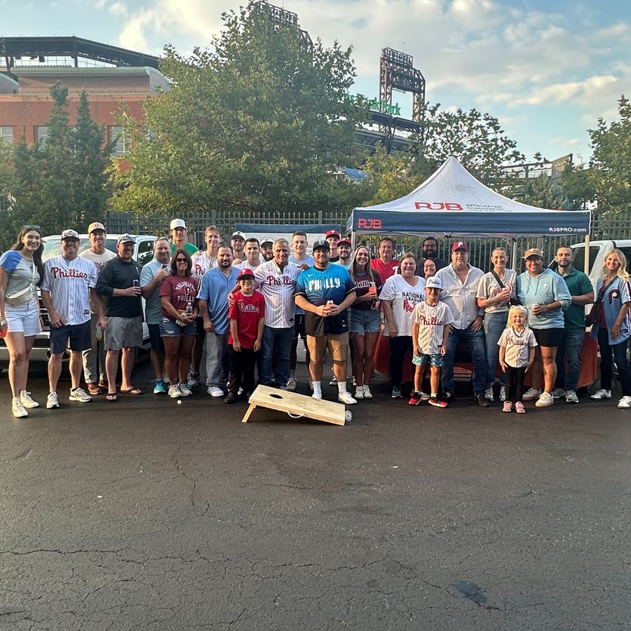 Large group of RJB employees and families in Phillies gear at a tailgate outside the ballpark