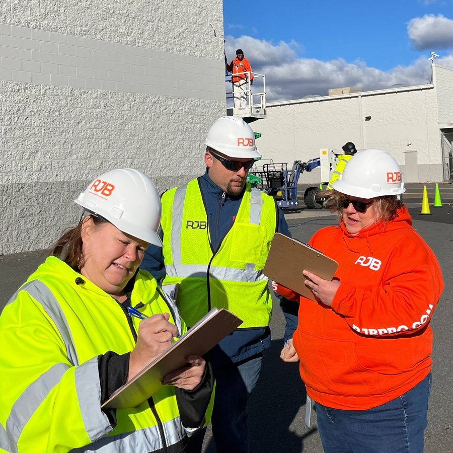 RJB team members in hard hats and high-visibility gear reviewing clipboards on a jobsite