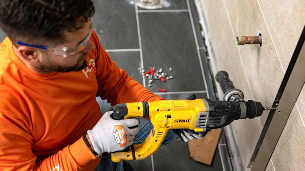 RJB employee using a drill to drill a screw into a wall on the interior of a building