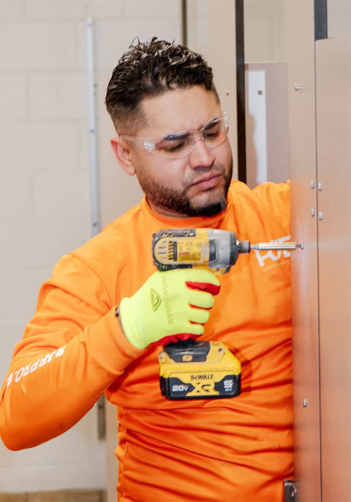 RJB employee drilling a screw into a bathroom stall