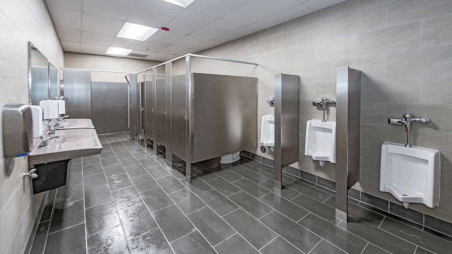 Freshly renovated bathroom with multiple stalls and urinals