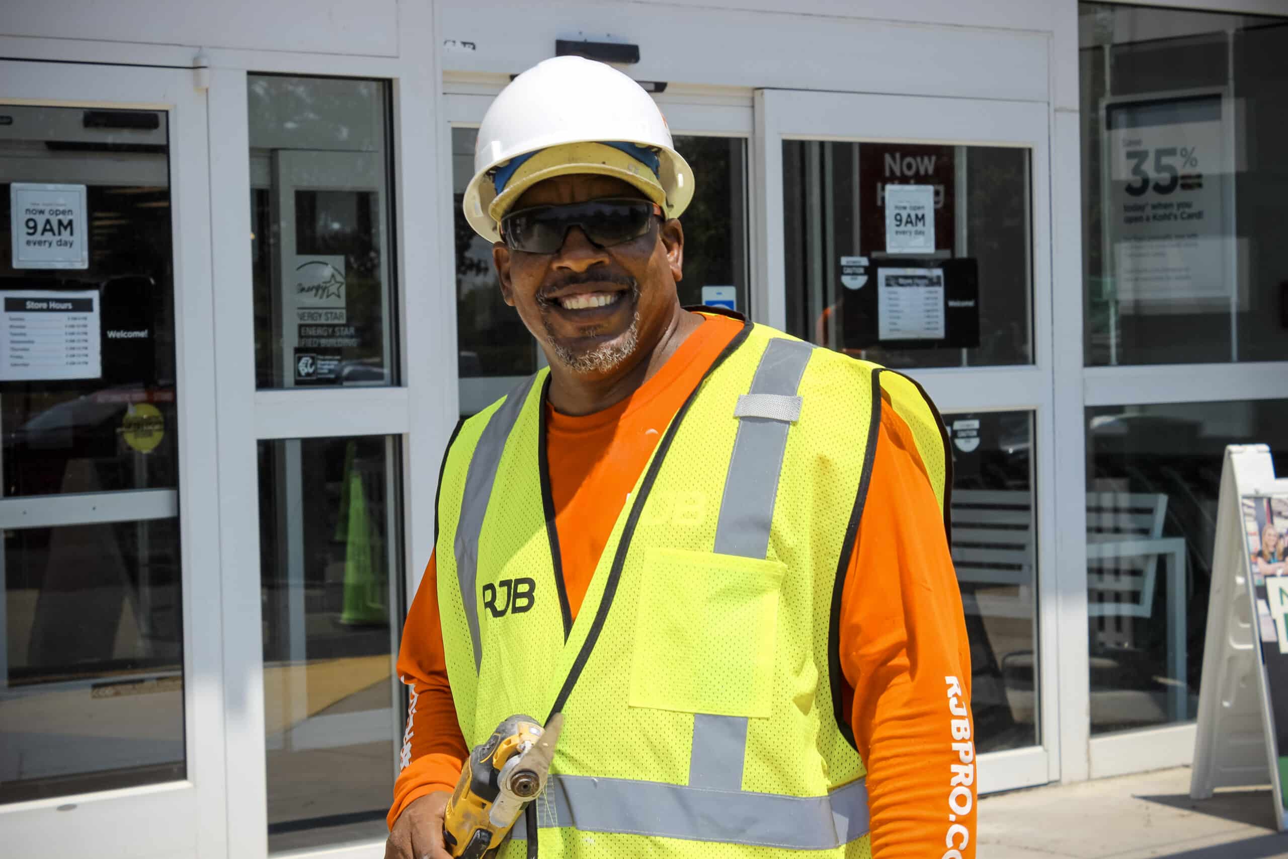 RJB Employee smiling in front of a retail building during a building coating project